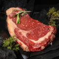 Ein rohes Ribeye Steak vor dunklem Hintergrund