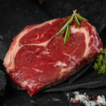 Ein Stück rohes Ribeye Steak auf dunklem Hintergrund